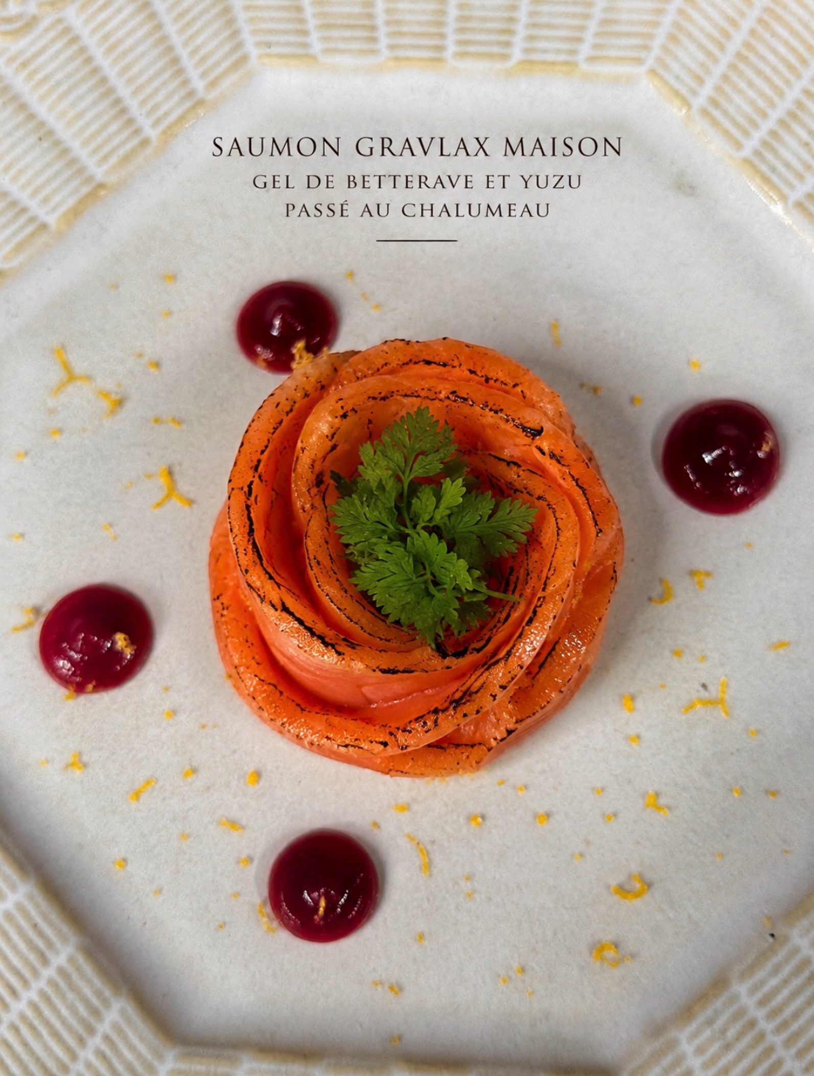 Saumon gravlax maison, délicatement passé au chalumeau pour apporter de subtiles notes fumées et une légère caramélisation qui révèlent toute la richesse du poisson. Le gel de betterave offre une douceur délicate, tandis que le yuzu apporte une fraîcheur acidulée qui équilibre l’ensemble et apporte une véritable signature gustative. Une entrée raffinée où chaque élément a été pensé pour créer une harmonie de saveurs et offrir une expérience aussi élégante que gourmande.